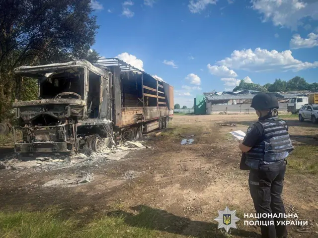 Поліцейський стоїть біля спаленої вантажівки