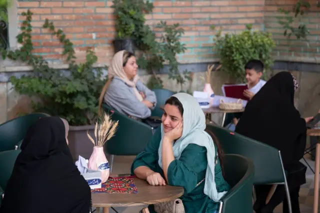 چند زن با حجاب در یک رستوران نشسته‌اند و با هم صحبت می‌کنند