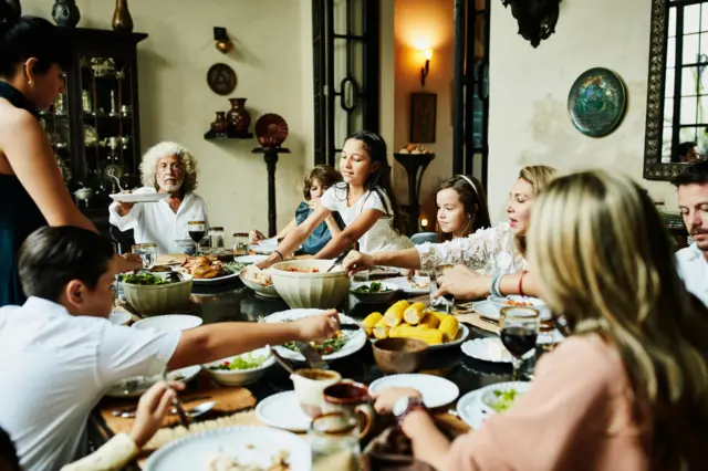 Uma família latina reunida à mesa durante uma refeição