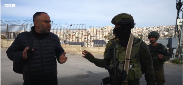 عيسى يقف إلى جوار جندي إسرائيلي