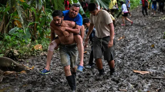 Homem carrega ferido perto de Lajas Blancas, na região de Darién (Panamá)