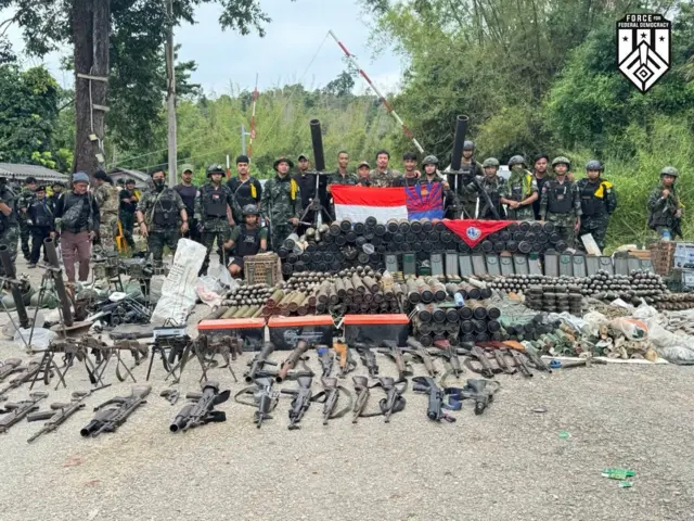 ကရင်အလံကိုင်ထားတဲ့ တော်လှန်ရေးတပ်ဖွဲ့ဝင်တွေနဲ့ ဖြန့်ခင်းထားတဲ့ လက်နက်ခဲယမ်းတွေ 