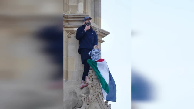 رجل يحمل العلم الفلسطيني ويتحدث في الهاتف وهو يقف على برج إليزابيث