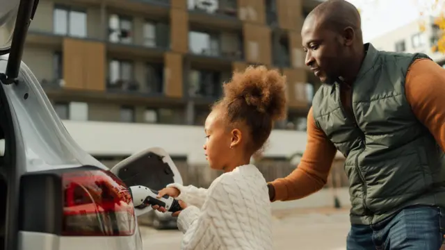 پدری به دخترش برای شارژ خودروی برقی کمک میکند