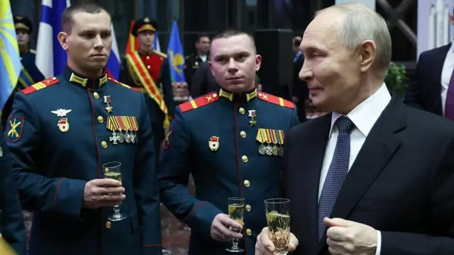 ولادیمیر پوتین، رئیس‌جمهور روسیه با گیلاس شامپاین در دست کنار دو چهره نظامی  روسیه با یونیفرم نظامی