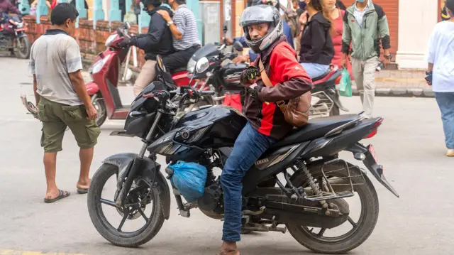 सडकमा हेल्मेट लगाएर मोटरसाइकममा बसेका एक युवा