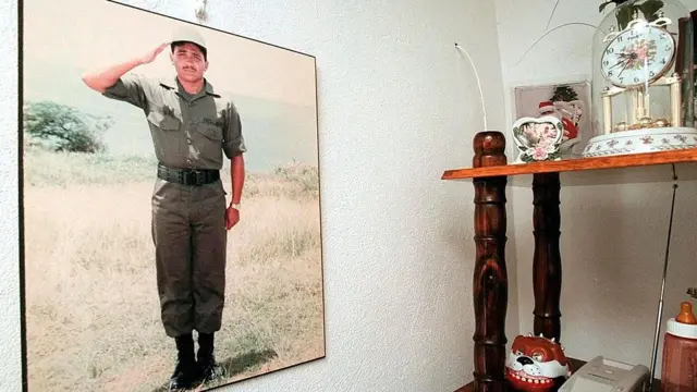 Un cuadro colgado en una pared con una imagen de david sanes haciendo un saludo militar. 