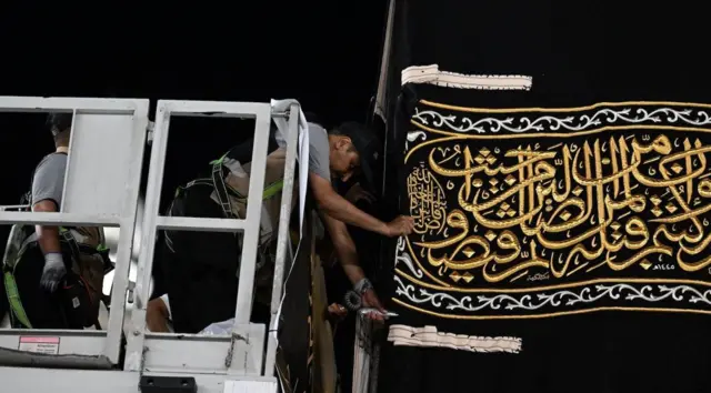 عُمال يقومون بخياطة قطع من الكسوة الجديدة (القماش الحريري الذي يغطي الكعبة) يدوياً في المسجد الحرام بمكة المكرمة، المملكة العربية السعودية، في 7 يوليو/ تموز 2024.