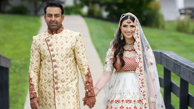 Sammi Cannold e Safi Rauf, de mãos dadas, posam para uma foto com trajes de casamento. Ela usa um vestido tradicional afegão de noiva, branco e vermelho, com lenço na cabeça; ele veste um sherwani, traje dourado típico de noivos.