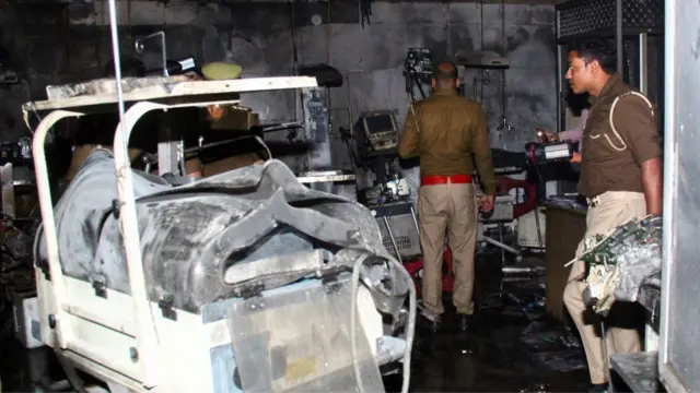 Police officers examine the damaged neonatal intensive care unit after a fire broke out at the Maharani Laxmibai Medical College in Jhansi district, in the northern state of Uttar Pradesh,