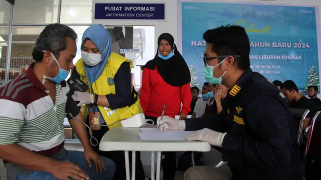 Petugas medis memeriksa tekanan darah seorang pekerja migran Indonesia yang dideportasi dari Malaysia di Terminal Penumpang Pelabuhan Pelindo Dumai, di Dumai, Riau, Sabtu (20/1).