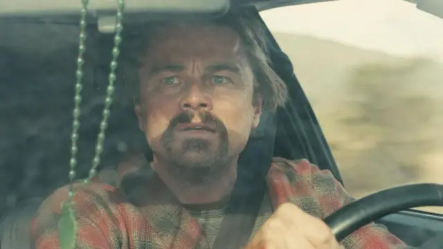 Leonardo DiCaprio conduce un auto y mira por el espejo retrovisor con cara de susto