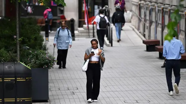 Pessoas caminhando numa calçada larga