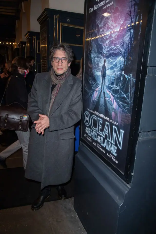 Нил Гейман на фоне афиши спектакля «Океан в конце дороги».