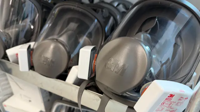 Dos mascarillas grises se exhiben en un soporte con paneles transparentes para el rostro.