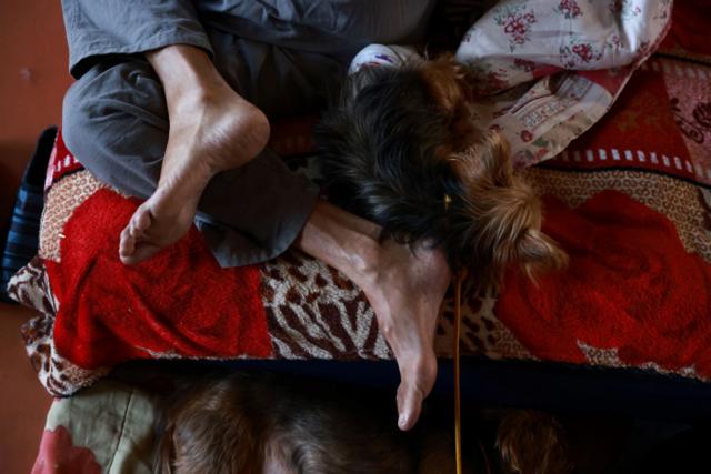 Foto de pessoa sem sapatado deitada ao lado de seu cachorro