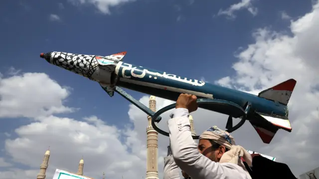 يمني مناصر لجماعة أنصار الله يرفع مجسماً لصاروخ "فلسطين-2" في العاصمة صنعاء