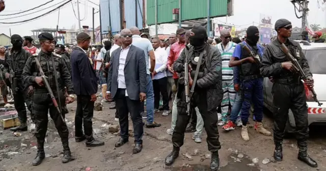 Gentiny Ngobila Mbaka, Guverineri wa Kinshasa, uri hagati, ari kureba ibikorwa byo gusukura umujyi arinzwe n'abantu bitwaje intwaro 