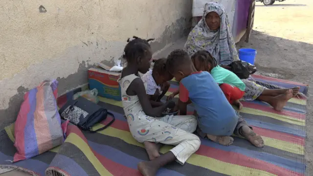 Woman and children siddon on top mat