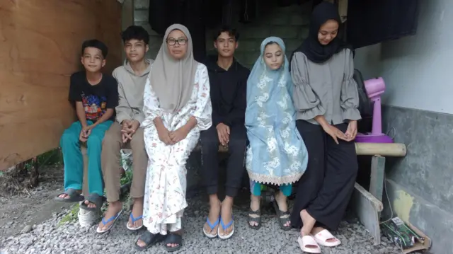 Rusehan dan anak-anaknya. Rusehan duduk di baris ketiga, dua anak laki-laki di sebelah kirinya, satu anak laki-laki dan dua anak perempuan di sebelah kanan.