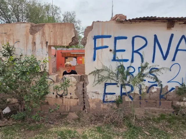 Mujer en la ventana de una casa rota