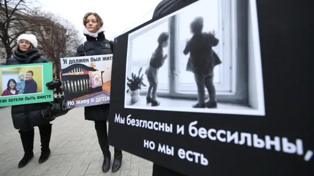 Люди стоят в пикете с плакатами, на одном надпись «Мы безгласны и бессильны, но мы есть»
