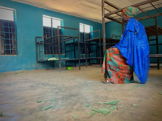 Une femme assise dans une pièce avec des lits superposés vides et d'objets éparpillés à l'intérieur d'un dortoir d'étudiants de l'école catholique St. Mary's à Papiri, dans la zone de gouvernement local d'Agwarra, dans l'État du Niger. 