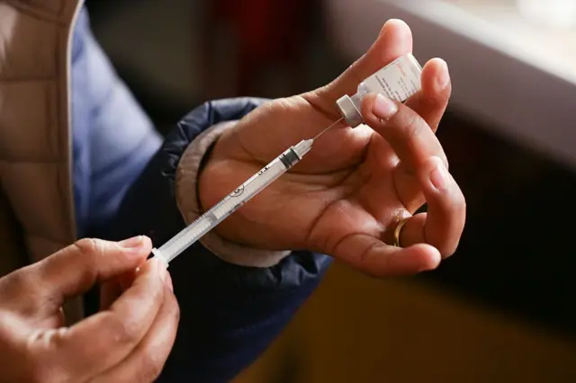 Bir erkek elinin HPV aşısını şırıngaya enjekte ettiği görülüyor. 