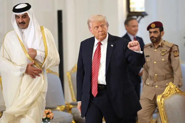 কাতারের আমিরের সঙ্গে হেঁটে যাচ্ছেন ডোনাল্ড ট্রাম্প, পেছনে সামরিক ও বেসামরিক পোশাকে দুই জনকে দেখা যাচ্ছে
