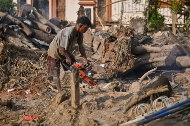 Warga korban banjir bandang dan longsor menggergaji sampah kayu di Hutanabolon, Kecamatan Tukka,Tapanuli Tengah, Sumatera Utara, Rabu (24/12/2025).