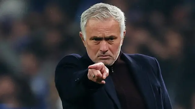 Jose Mourinho points as he wears a blue jacket above a zip-up top