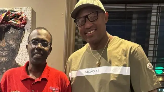 Antoine Marie Zacharie Rugerinyange 'Africa Nova', Félin Gakwaya na Jean Claude Bikamba bahagaze bareba muri 'camera' bamwenyura. Inyuma yabo hari urukuta ruriho ishusho ikoze mu irangi y'umuntu uteze igitambaro mu mutwe cyo mu gitenge.