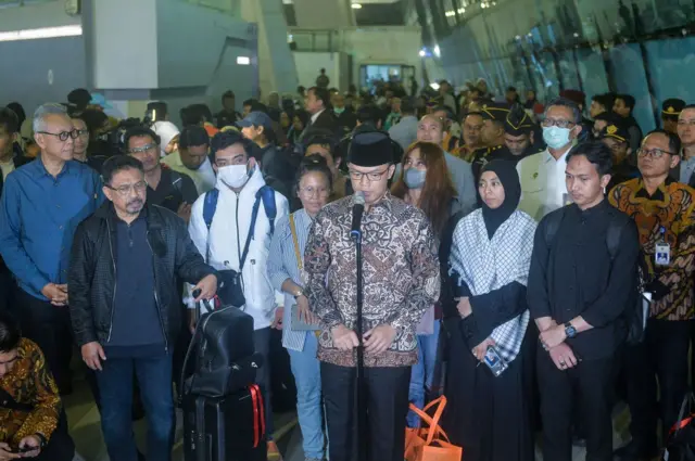 Menlu Sugiono dengan menggunakan stelan batik dan berpeci berada di tengah-tengah WNI yang berhasil dipulangkan dari Iran.