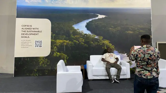 Um homem negro tira foto de outro homem negro que está sentado em uma poltrona