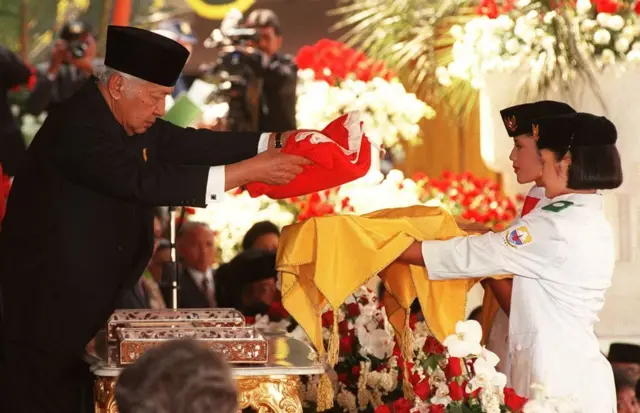 Presiden Indonesia Soeharto menyerahkan bendera nasional sebelum dikibarkan dalam perayaan HUT ke-52 kemerdekaan negara tersebut di Istana Kepresidenan pada tanggal 17 Agustus. Presiden pertama Soekarno memproklamasikan kemerdekaan dari penjajah Belanda 52 tahun silam, setelah pasukan pendudukan Jepang menyerah kepada pasukan Sekutu. (Foto oleh