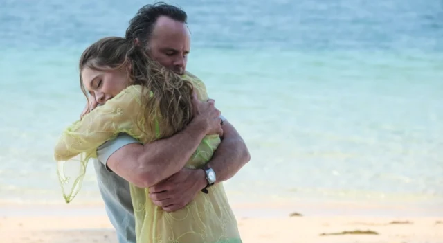 Un hombre y una mujer, abrazados junto al mar. 