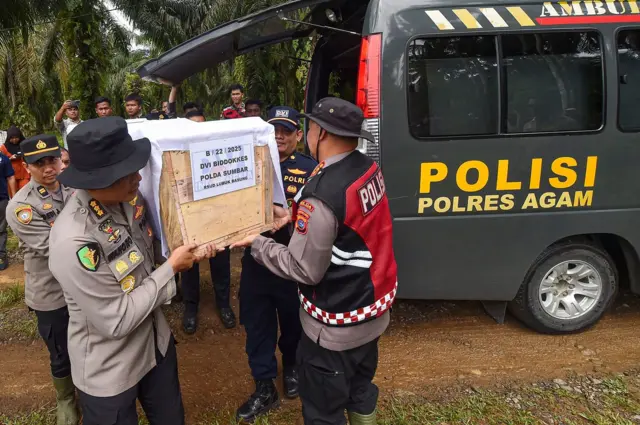 Petugas kepolisian membawa peti jenazah korban banjir bandang saat pemakaman massal di Tempat Pemakaman Umum (TPU) Kampuang Baru, Nagari Sungai Jariang, Agam, Sumatera Barat, Kamis (11/12/2025).