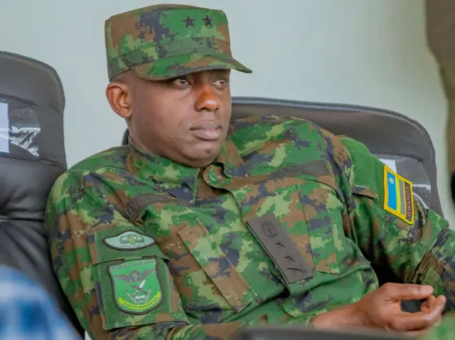 Jenerali Majoro Ruki Karusisi yicaye ku ntebe yambaye imyenda ya gisirikare. 