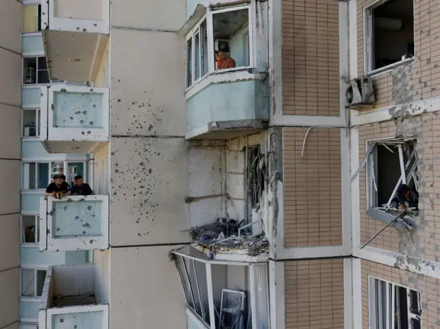 Вид снаружи на квартиру в много этажно доме, в которую попал дрон. Видно разрушенный балкон, выбитые окна в квартире и соседних и следы осколков на стенах.