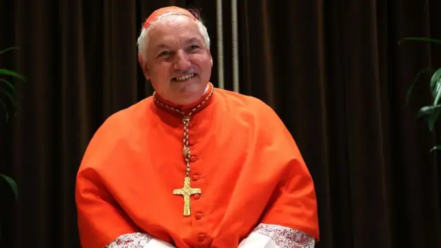 Jean-Marc Aveline poses in a red top with a gold cross