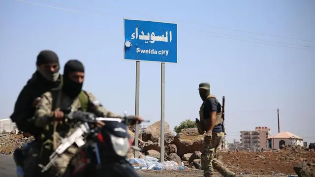 صورة أرشيفية بتاريخ  19 يوليو/تموز 2025 لمسلحين على متن رداجة نارية، وجههما ملثم في في الحي الغربي لمدينة السويداء ذات الأغلبية الدرزية بجنوب سوريا
