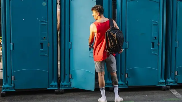 Homem abrindo a porta de um banheiro público com as mãos na maçaneta