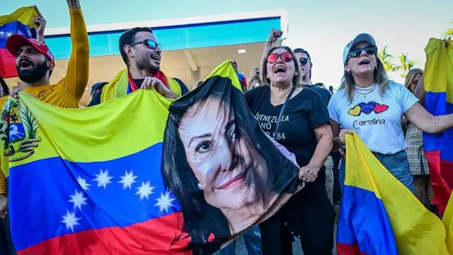Venezolanos sostienen una pancarta con el rostro de María Corina Machado en una manifestación en Doral el 3 de enero de 2026.