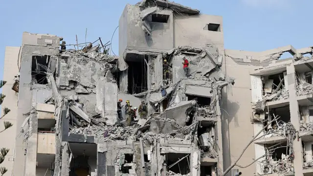 Berşeeba'da vurulan apartmanın enkazında görevliler var. Altı görevli enkazda yaralı ya da ölü var mı arıyor, aralarında konuşuyor
