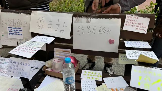 メッセージが書かれた大小の紙が置かれたり、テープで貼られたりしている。ペットボトルの水も置かれている