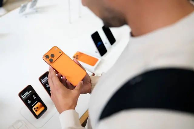 Un usuario el la tienda de Apple toma un nuevo iPhone 17 en sus manos.