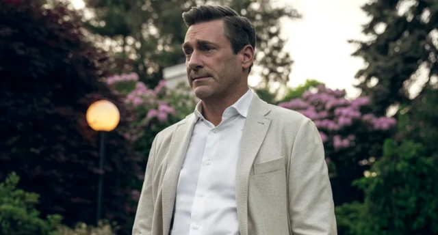 Un hombre con traje de chaqueta sin corbata en una calle. Tiene expresión atribulada. 