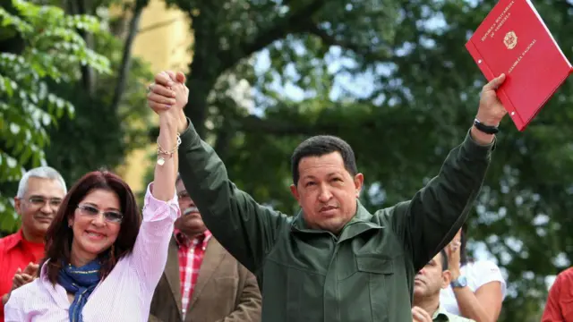 Cilia Flores e Hugo Chávez levantam os braços em evento público