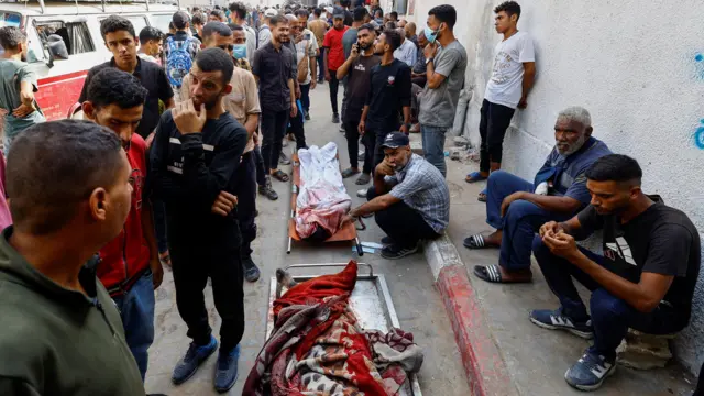 مشيعون يتجمعون بجوار الجثث في جنازة فلسطينيين قُتلوا بنيران إسرائيلية أثناء محاولتهم الحصول على المساعدات الإنسانية.