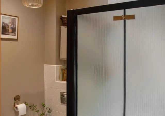 Czarna kabina prysznicowa z panelami o efekcie ryflowanego szkła.